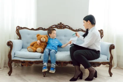 A calm, professional clinic setting with a parent and child speaking with a clinician about psychological testing, with subtle educational materials nearby.