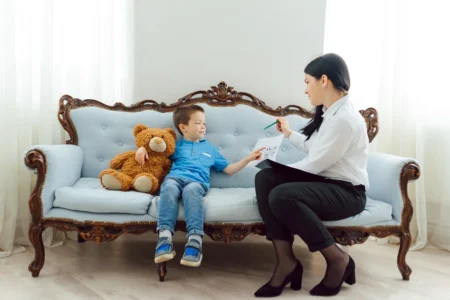 A calm, professional clinic setting with a parent and child speaking with a clinician about psychological testing, with subtle educational materials nearby.